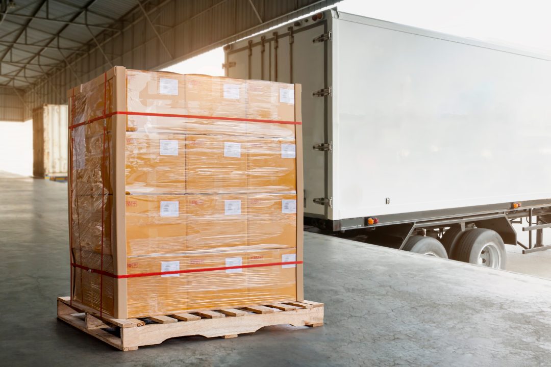 Cargo Trailer Truck Parked Loading at Dock Warehouse. Freight Truck. Shipment. Delivery Service. Package Boxes on Pallet Waiting to Load into Container Truck. Supply Chain. Logistics Transportation.