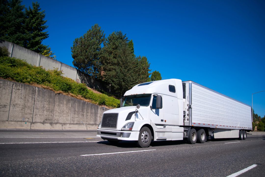 Blanco moderno Big Rig semirremolque con semirremolque frigorífico equipado con unidad de refrigeración va en la carretera plana de ancho con la carga comercial para la entrega al almacén