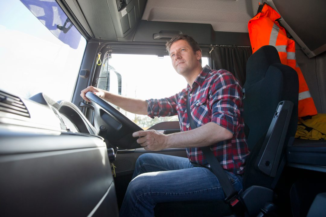 Truck driver driving in cab of semi-truck