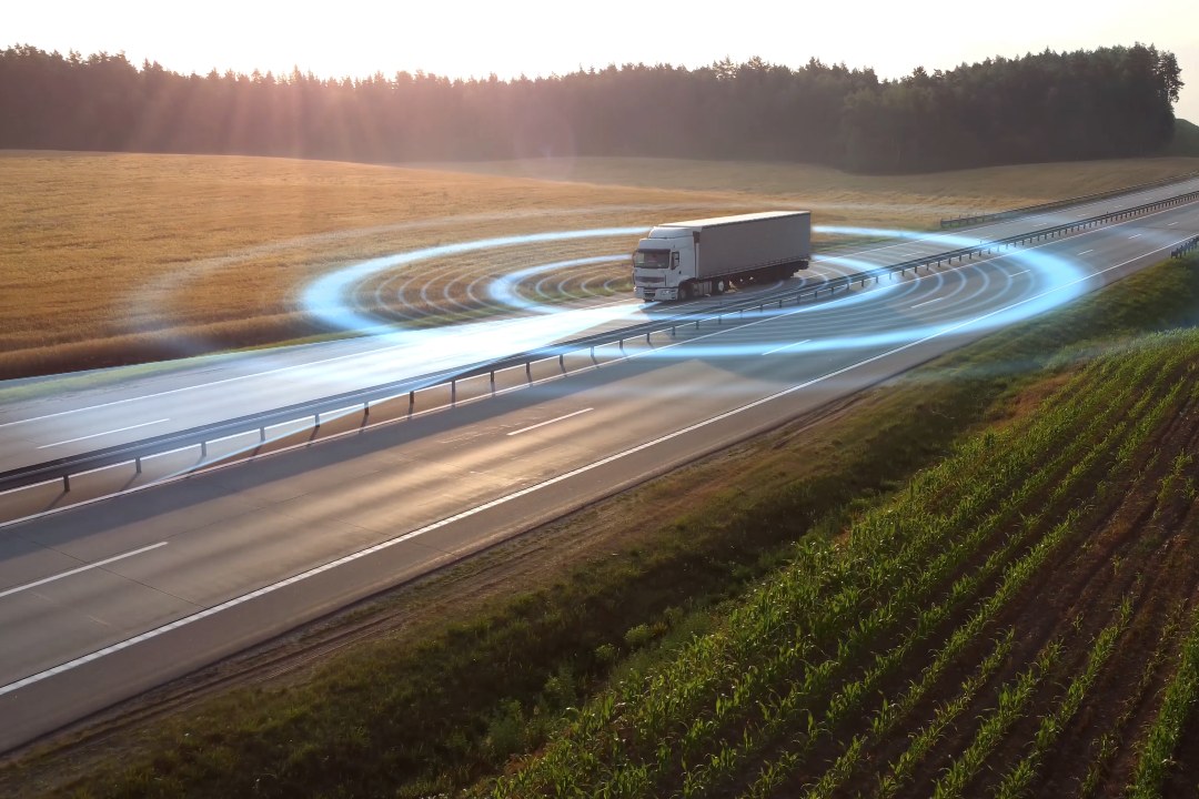 Aerial view of autonomous truck driving on autopilot on a highway with traffic sensors scanning surroundings.