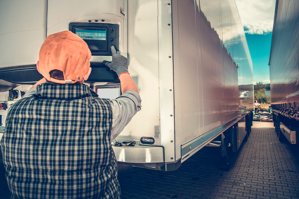  A man in a vest and hat stands beside a truck, highlighting cross-border food transport practices for Tijuana-San Diego routes.