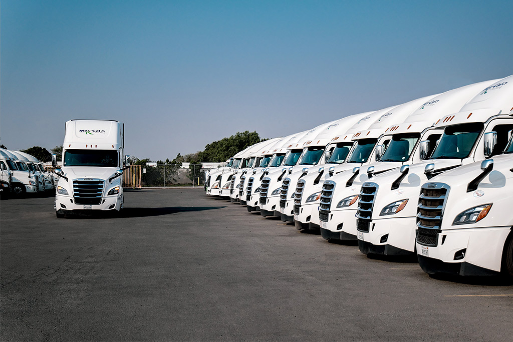 Mexcal trucks flotilla. A row of white semi trucks parked in a lot, ready for equipment relocations from Tijuana to US manufacturing hubs.