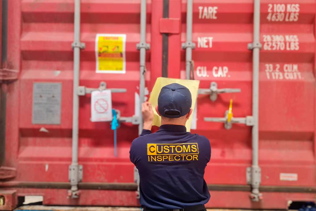 A man wearing a blue shirt is seen holding a box, representing the customs process at Otay Mesa Border.