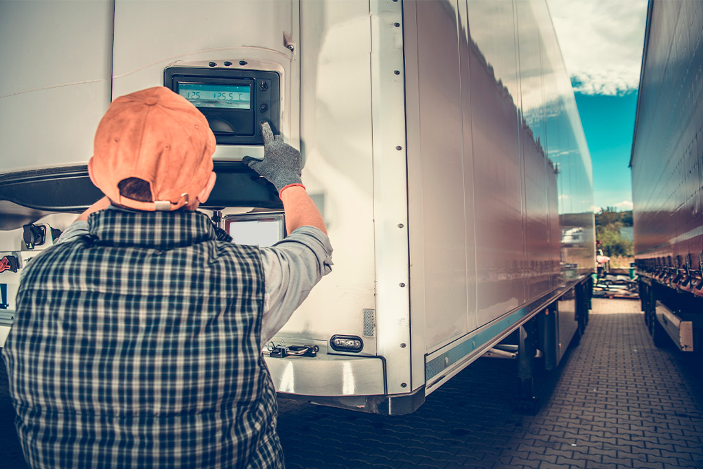 A man wearing a vest and hat stands next to a truck, readying for the holiday season's pharmaceutical transport demands.