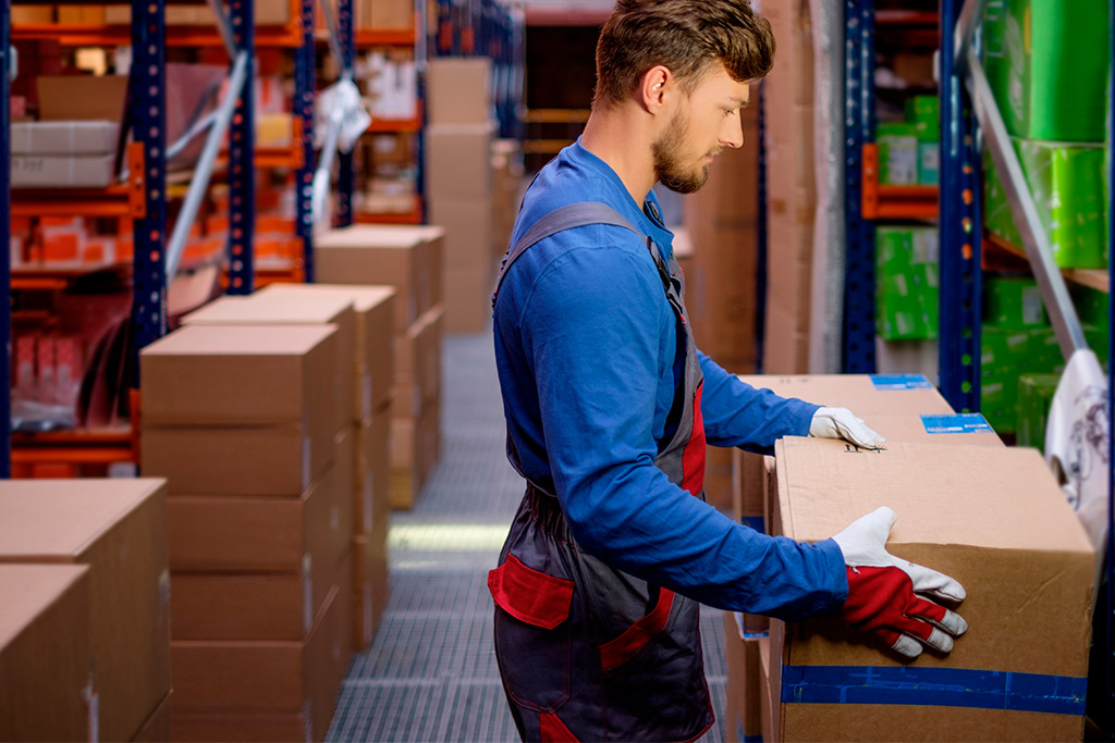 A warehouse scene featuring a man managing boxes on shelves, relevant to optimizing aftermarket auto parts shipping costs.